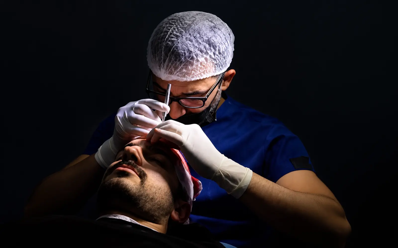 Surgeon performing a nasal and facial procedure under surgical lighting
